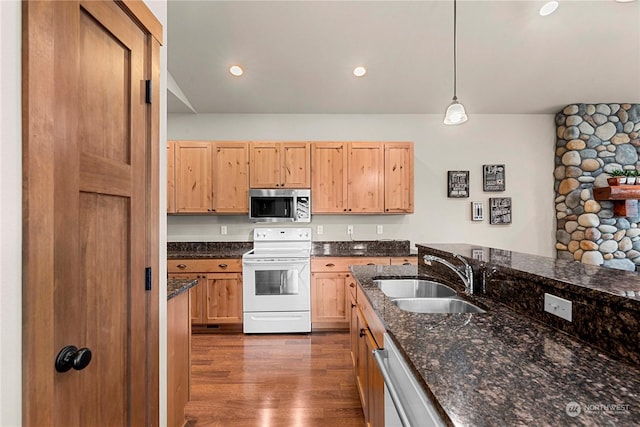 kitchen featuring pendant lighting, appliances with stainless steel finishes, dark stone counters, sink, and dark hardwood / wood-style floors