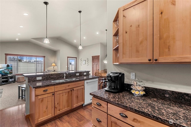 kitchen with lofted ceiling, dishwasher, pendant lighting, sink, and dark stone counters