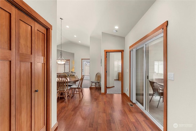 hallway with dark wood-type flooring and lofted ceiling