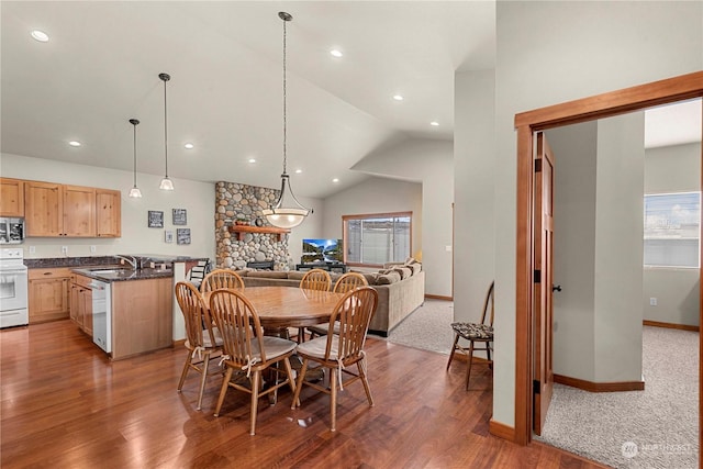 dining space featuring vaulted ceiling, a fireplace, sink, and dark hardwood / wood-style floors