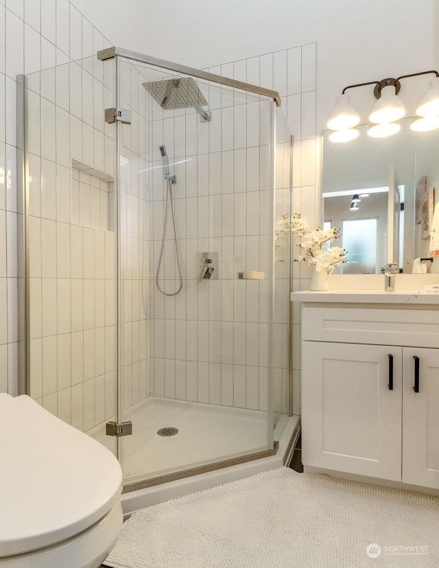 bathroom featuring a shower with shower door, toilet, and vanity