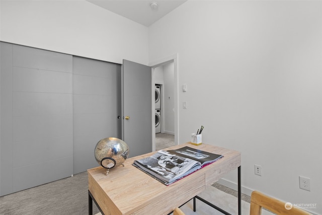 carpeted office space featuring stacked washer and clothes dryer