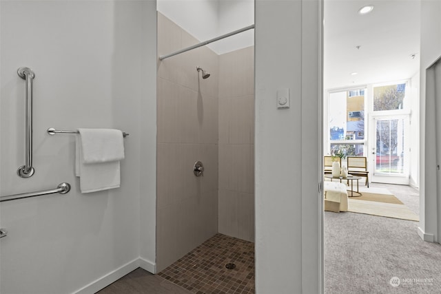 bathroom featuring a tile shower, plenty of natural light, and floor to ceiling windows