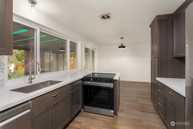 kitchen featuring sink, hanging light fixtures, dishwasher, kitchen peninsula, and electric stove