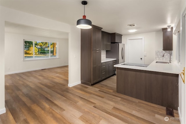 kitchen with dark brown cabinets, sink, stainless steel fridge, and black electric cooktop