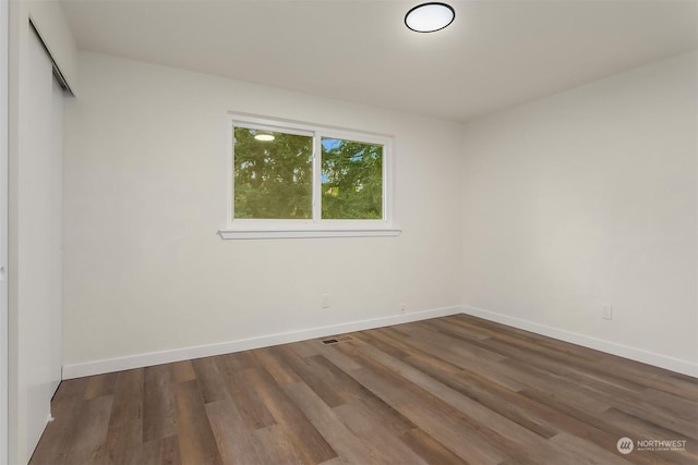 unfurnished room with dark wood-type flooring