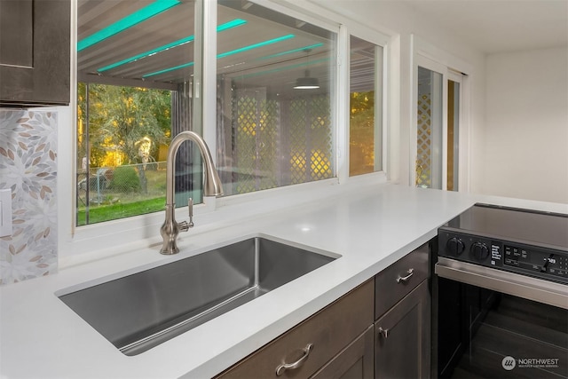 kitchen featuring range with electric stovetop, sink, and dark brown cabinetry