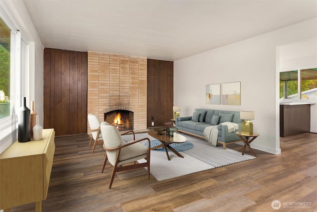 living room with hardwood / wood-style floors, a brick fireplace, and wood walls