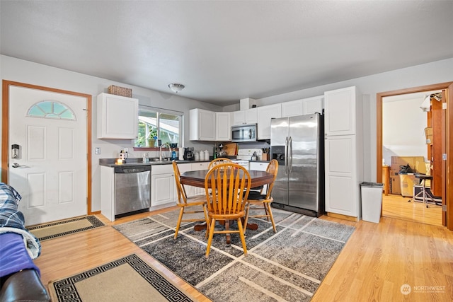 kitchen featuring appliances with stainless steel finishes, light hardwood / wood-style floors, white cabinets, and sink