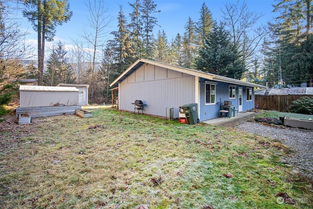 view of side of home featuring a lawn and a storage shed