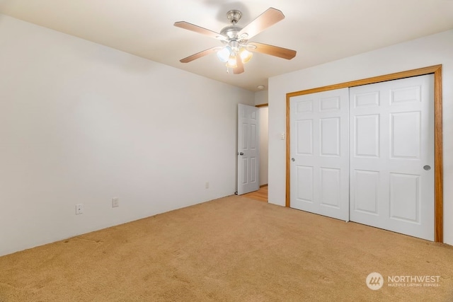 unfurnished bedroom with ceiling fan, a closet, and light carpet