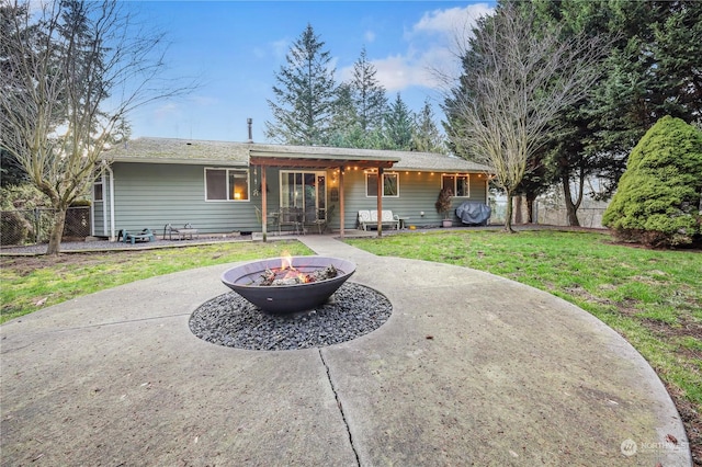 rear view of property featuring a lawn and an outdoor fire pit