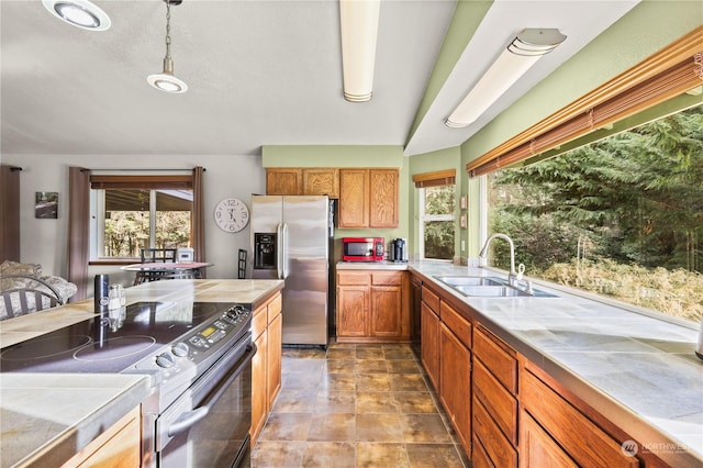 kitchen featuring sink, hanging light fixtures, electric range, stainless steel fridge, and a healthy amount of sunlight