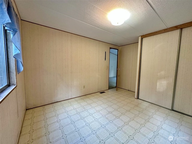 empty room with a textured ceiling and wood walls