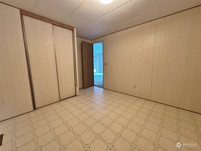 unfurnished bedroom featuring a closet and wooden walls