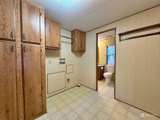 laundry room featuring washer hookup, cabinets, a textured ceiling, and wood walls