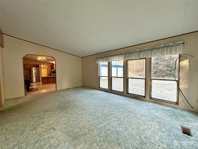 unfurnished living room featuring an inviting chandelier, lofted ceiling, and carpet floors