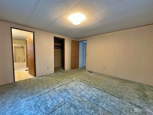 unfurnished bedroom with ensuite bathroom and wooden walls