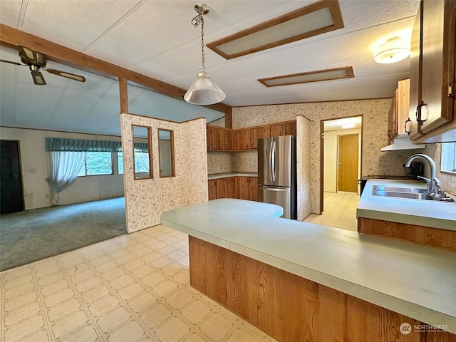 kitchen featuring decorative light fixtures, sink, stainless steel refrigerator, ceiling fan, and stove