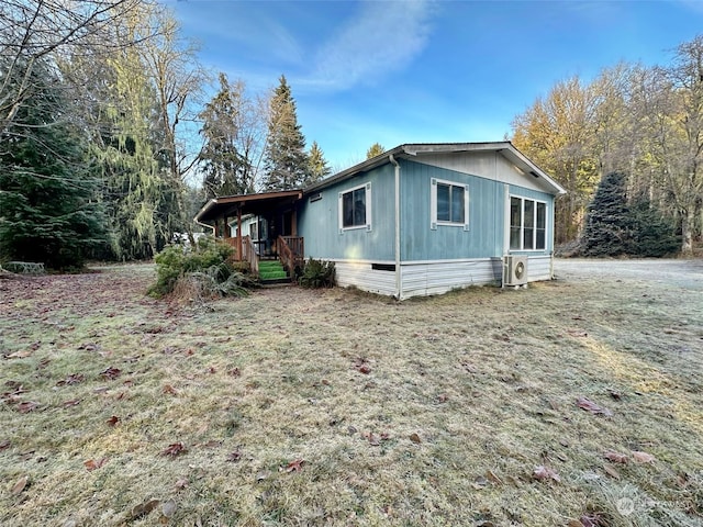 view of side of property with ac unit and a lawn