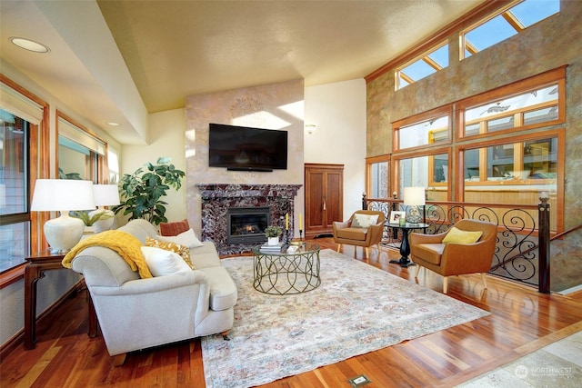 living room featuring a fireplace, hardwood / wood-style flooring, and a towering ceiling