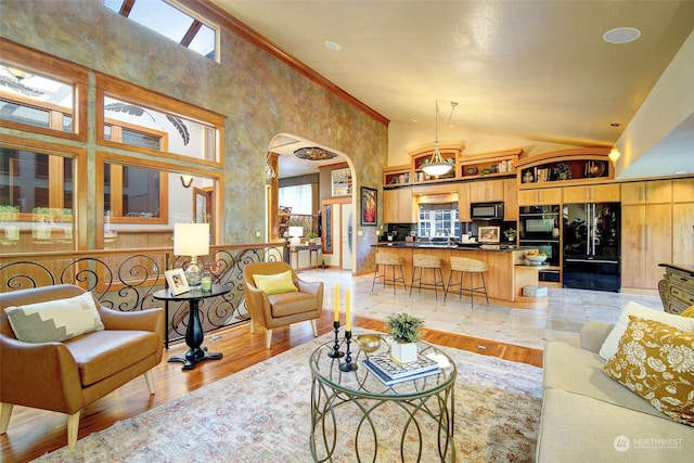 living room featuring high vaulted ceiling, a wealth of natural light, ornamental molding, and light wood-type flooring