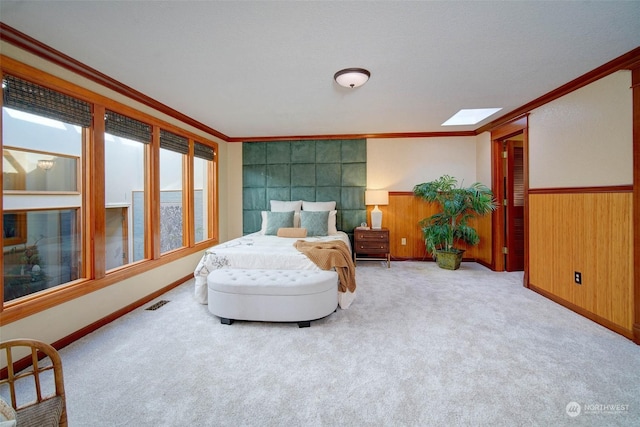 carpeted bedroom with a skylight, ornamental molding, and wooden walls