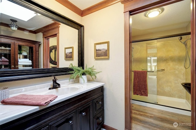 bathroom with crown molding, hardwood / wood-style flooring, walk in shower, and vanity