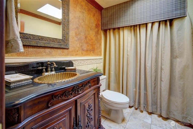 bathroom featuring tile patterned floors, vanity, a skylight, toilet, and crown molding