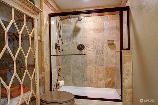 bathroom featuring toilet and a shower with door