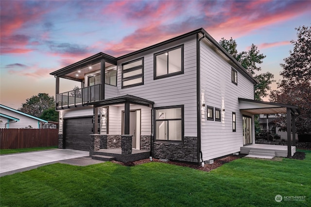 view of front of house featuring a garage, a balcony, and a yard