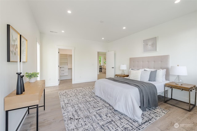 bedroom with a walk in closet and light wood-type flooring