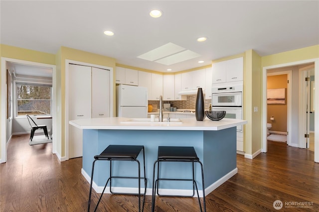 kitchen featuring white cabinets, white appliances, and light countertops