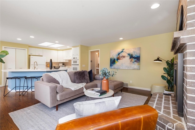 living room with a skylight, dark wood-style floors, visible vents, and recessed lighting