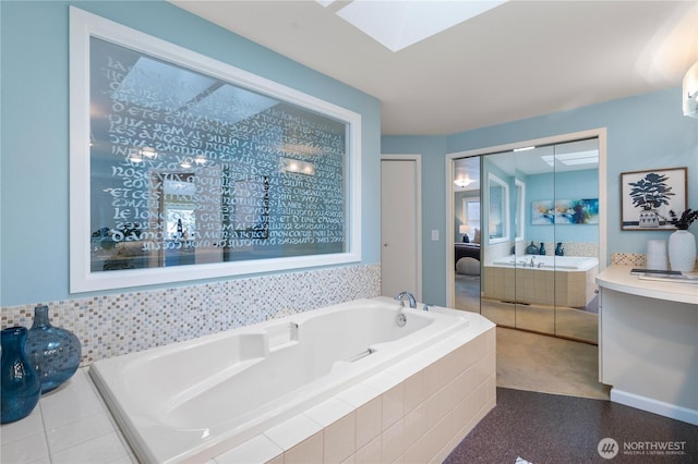 bathroom featuring a relaxing tiled tub, a skylight, and vanity