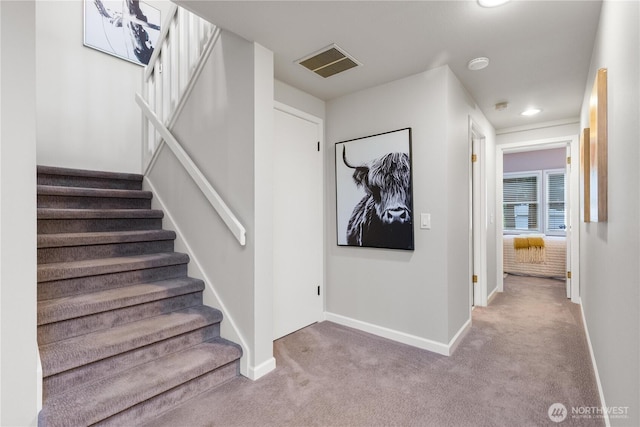 stairway with baseboards, visible vents, and carpet flooring