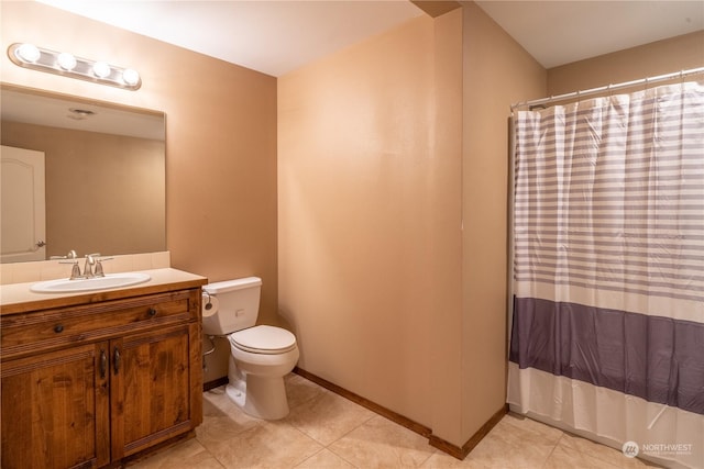 bathroom with toilet, vanity, and tile patterned flooring