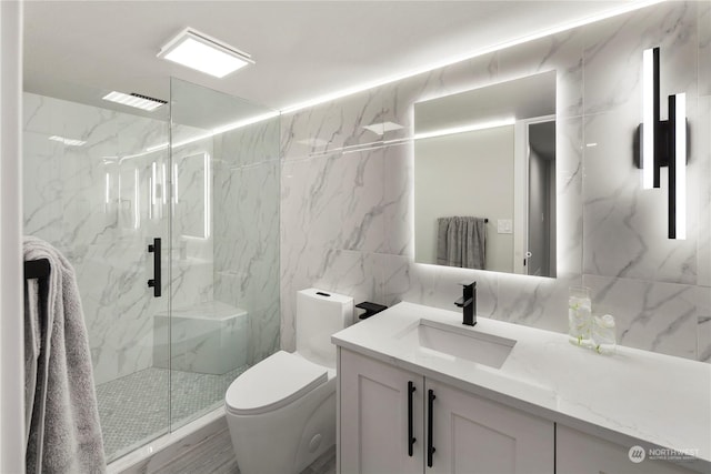 bathroom featuring vanity, toilet, a shower with shower door, and tile walls