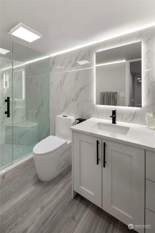 bathroom featuring hardwood / wood-style flooring, tile walls, vanity, an enclosed shower, and toilet