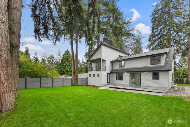 rear view of house with a wooden deck, a balcony, and a yard