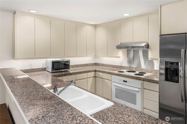 kitchen with exhaust hood, sink, stainless steel appliances, and cream cabinetry