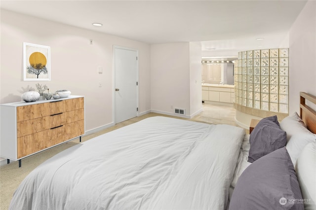 bedroom featuring light colored carpet and ensuite bath