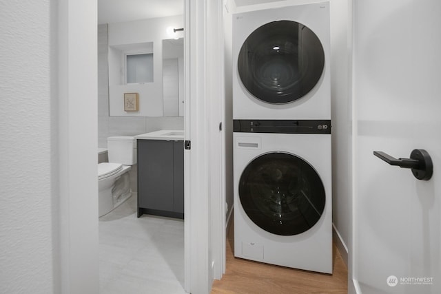 clothes washing area featuring light wood-type flooring and stacked washer / drying machine