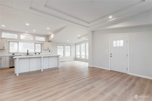 interior space featuring light hardwood / wood-style floors, white cabinets, tasteful backsplash, and a kitchen island