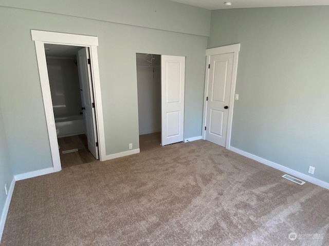 unfurnished bedroom with carpet floors, a closet, and ensuite bath