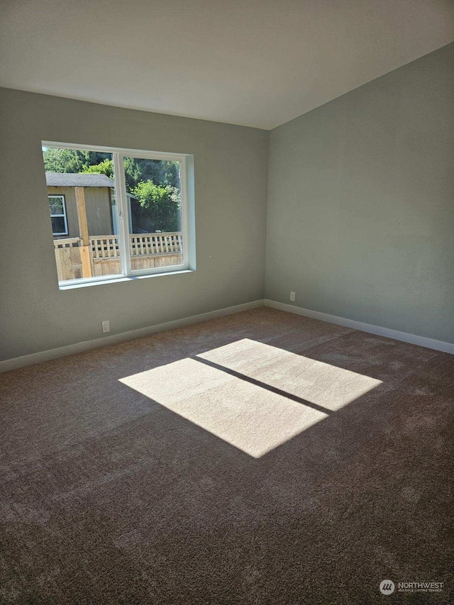 spare room featuring dark colored carpet