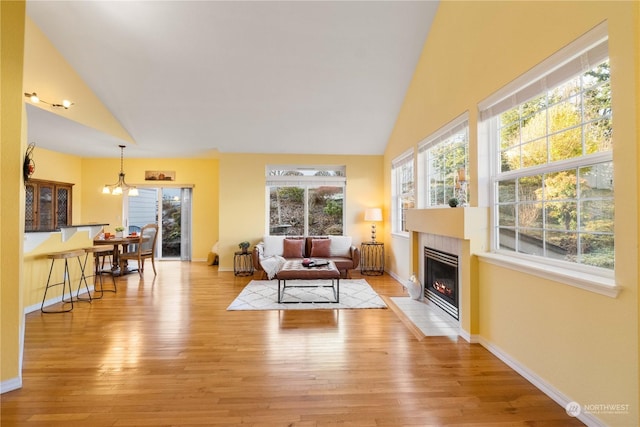 living room featuring light wood-type flooring, a chandelier, and high vaulted ceiling