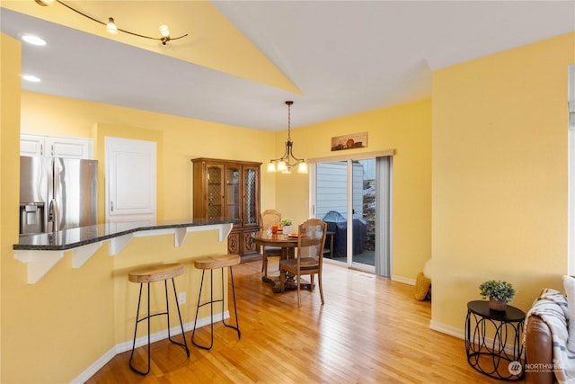 kitchen featuring pendant lighting, a kitchen bar, white cabinetry, light hardwood / wood-style floors, and stainless steel fridge with ice dispenser