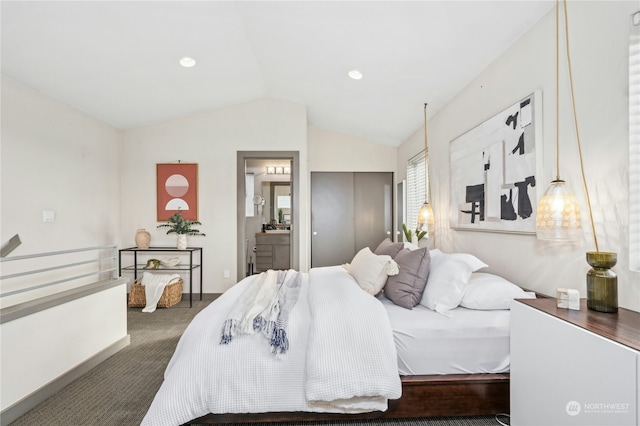 bedroom featuring dark colored carpet, lofted ceiling, and connected bathroom