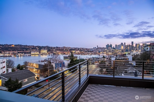 balcony at dusk featuring a water view